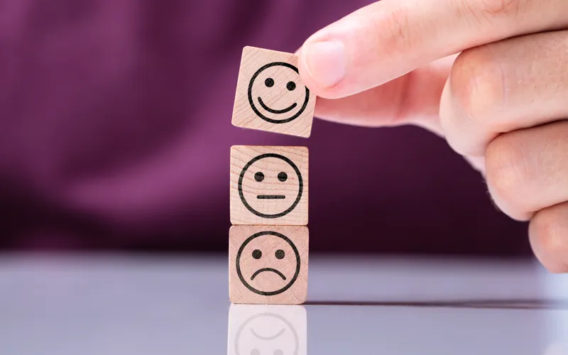 En person som håller i en träkloss med smileys på.