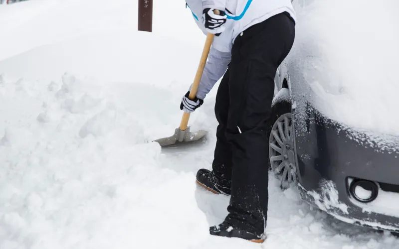 En person som skottar snö med en snöspade.