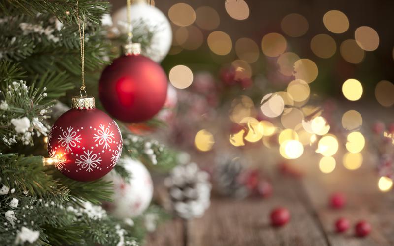 Julgran med röda julgranskulor och julgransbelysning i bakgrunden